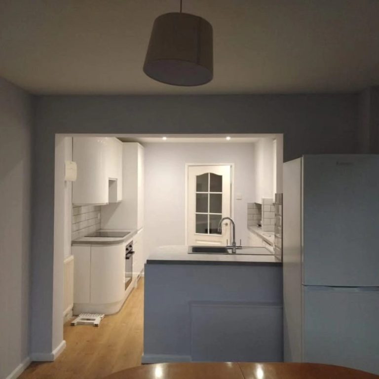 Modern kitchen with light-coloured cabinets and wooden flooring, featuring a sink and window.